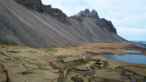 Islandia-Montañas-De-Drones-Junto-Al-Océano-Con-Escenario-De-Película-De-Pueblo-Vikingo-Stokksnes-Vestrahorn