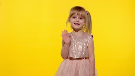 amigable niña rubia niño niña saludando a la cámara haciendo hola o adiós gesto, cámara lenta