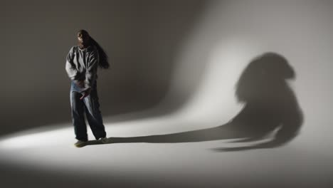 Full-Length-Studio-Portrait-Shot-Of-Young-Woman-Dancing-Casting-Shadow-With-Low-Key-Lighting-Against-Grey-Background-2