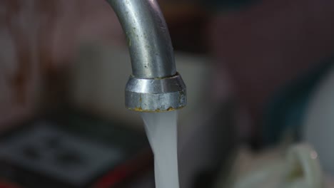 close-up of water flowing from kitchen tap from gush, trickle, to drips
