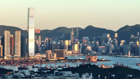 high skyline of hong kong city illuminated by the setting sun among the high mountains of green nature