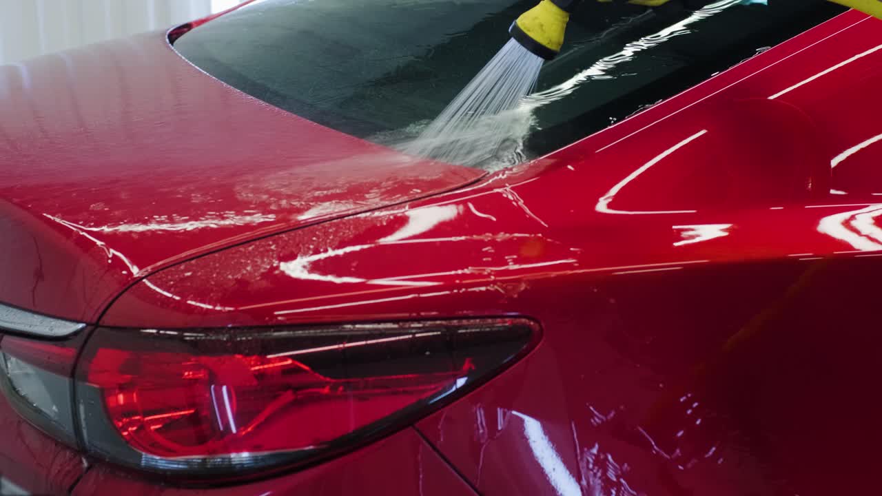 남자 노동자가 세탁장에서 빨간 차를 고 있다.