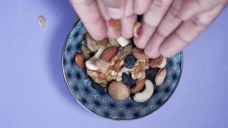Hands pouring mixed nuts and seeds into a bowl