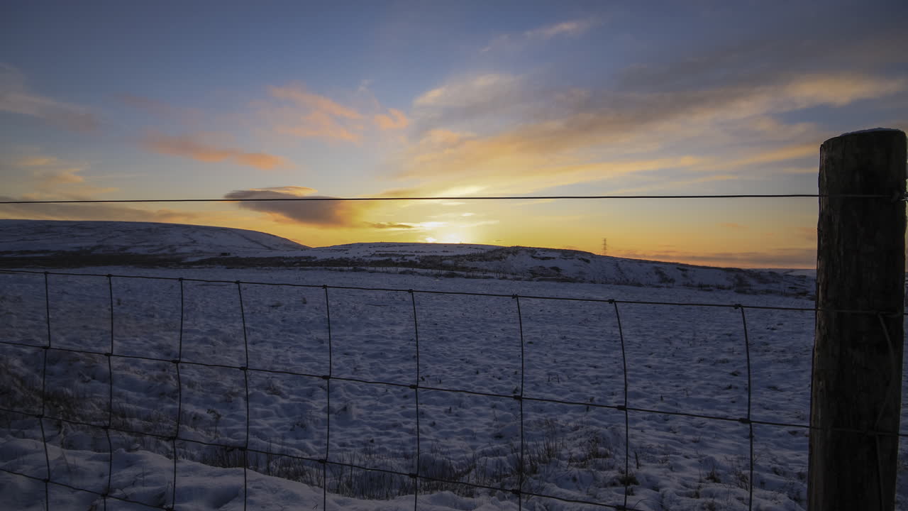 lapso de tiempo de un campo nevado con una puesta de sol y una cerca de ovejas de enlace abierto