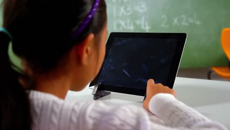 schoolgirl using digital tablet in classroom at school