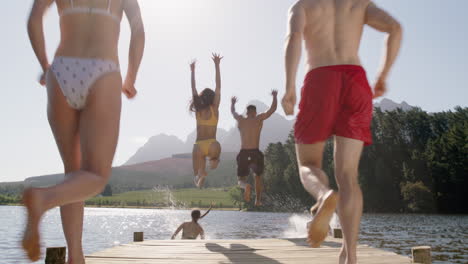 group of friends jumping in lake splashing in water having fun enjoying summer vacation