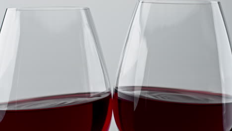 los vasos de bebidas rosadas brindando el gesto de primer plano. las copas de vino aplaudiendo juntas