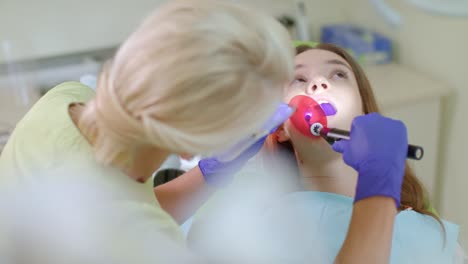 dentista que trabaja con lámpara de polimerización dental en la cavidad oral. tratamiento de los dientes