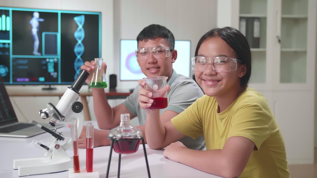 Young Asian Boy And Girl Smiling To Camera While Holding Tubes In Classroom. Study With Scientific Equipment. Education Concept