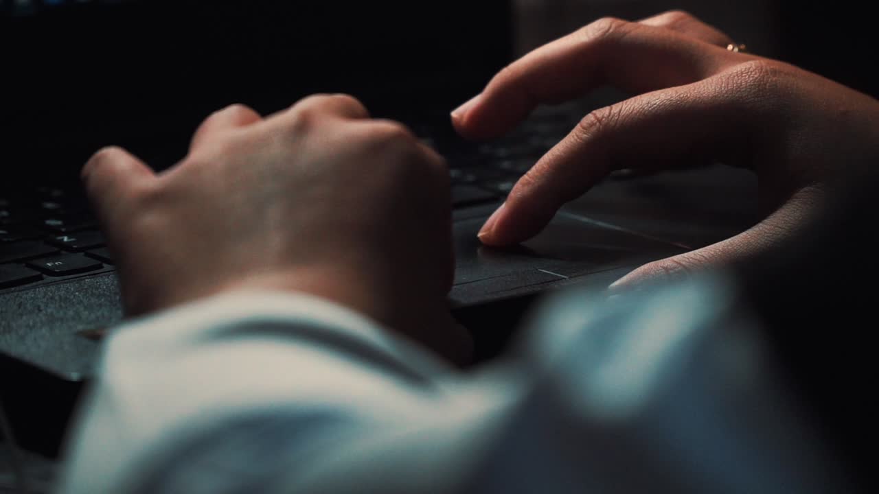 Close up of person typing wit hand on keyboard of laptop at night at home