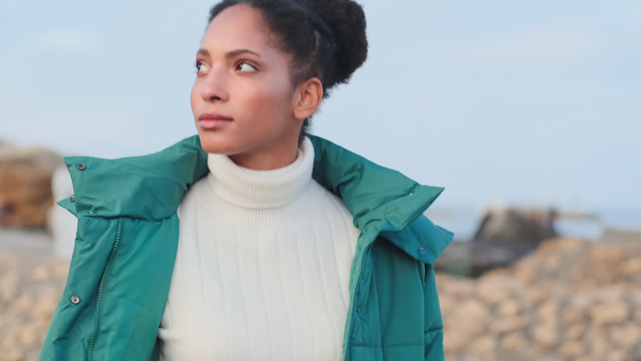 una chica afroamericana caminando por el mar.