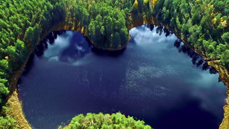 Calm-idyllic-lake-in-the-middle-of-dense-forests-on-a-sunny-autumn-day