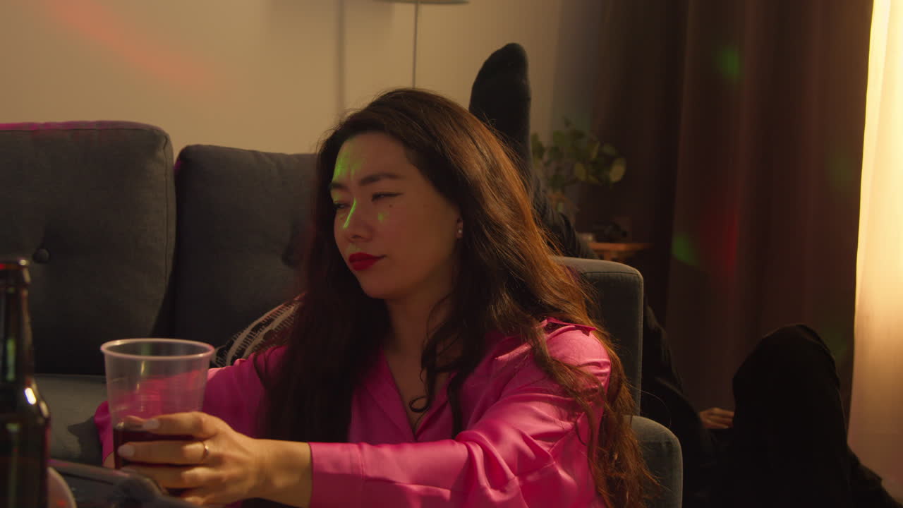 집 파티에서 소파 에 앉아있는 여자가 술을 충분히 마셨다고 결정합니다.