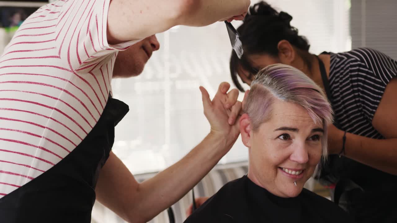 vista lateral mujer teniendo su cabello estilizado por dos peluqueros