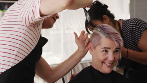 Side-view-woman-having-her-hair-styled-by-two-hairdressers