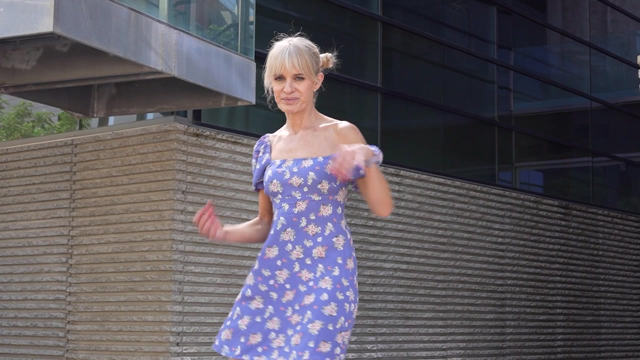 Una donna che emana sicurezza e stile cammina in un contesto urbano indossando un vestito floreale.