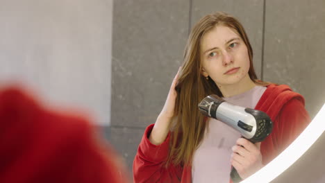 teenager drying hair in bathroom