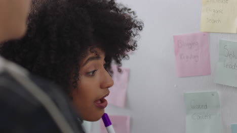 mixed race business woman using sticky notes training intern brainstorming with colleague sharing creative ideas for problem solving solution in office