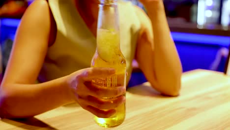 woman holding a cold beer at a bar