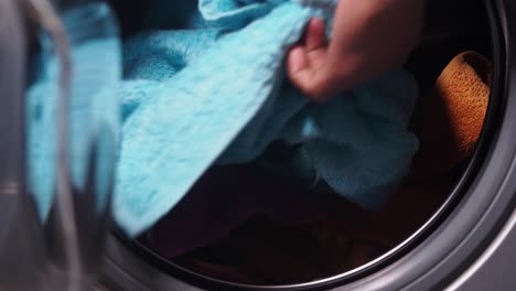 a person loading colorful towels into a washing machine