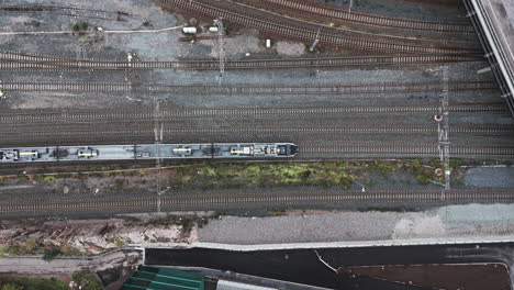 Top-shot-of-a-slow-train-and-locomotive-going-from-left-to-right-in-Pasila,-Helsinki,-Finland