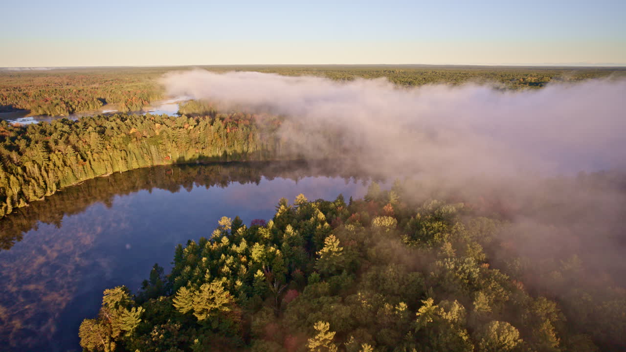 Drone footage of soft dawn mist rising over the water