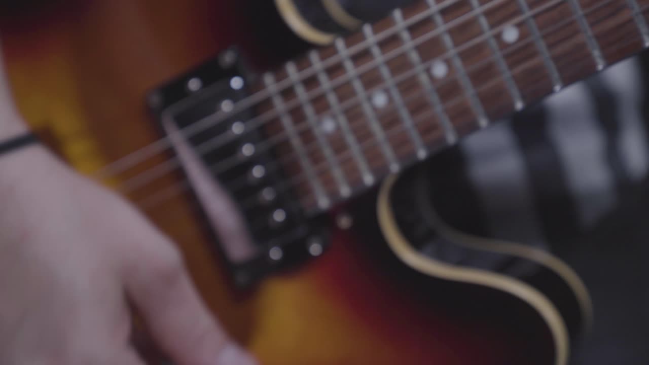 Man's hand strumming electric guitar, handheld close up, energetic feel