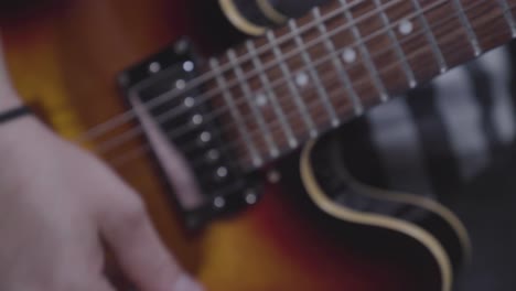 man's hand strumming electric guitar, handheld close up, energetic feel