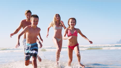 Parents-and-Children-In-Swimsuits-Running-Out-Of-Sea-On-Summer-Vacation