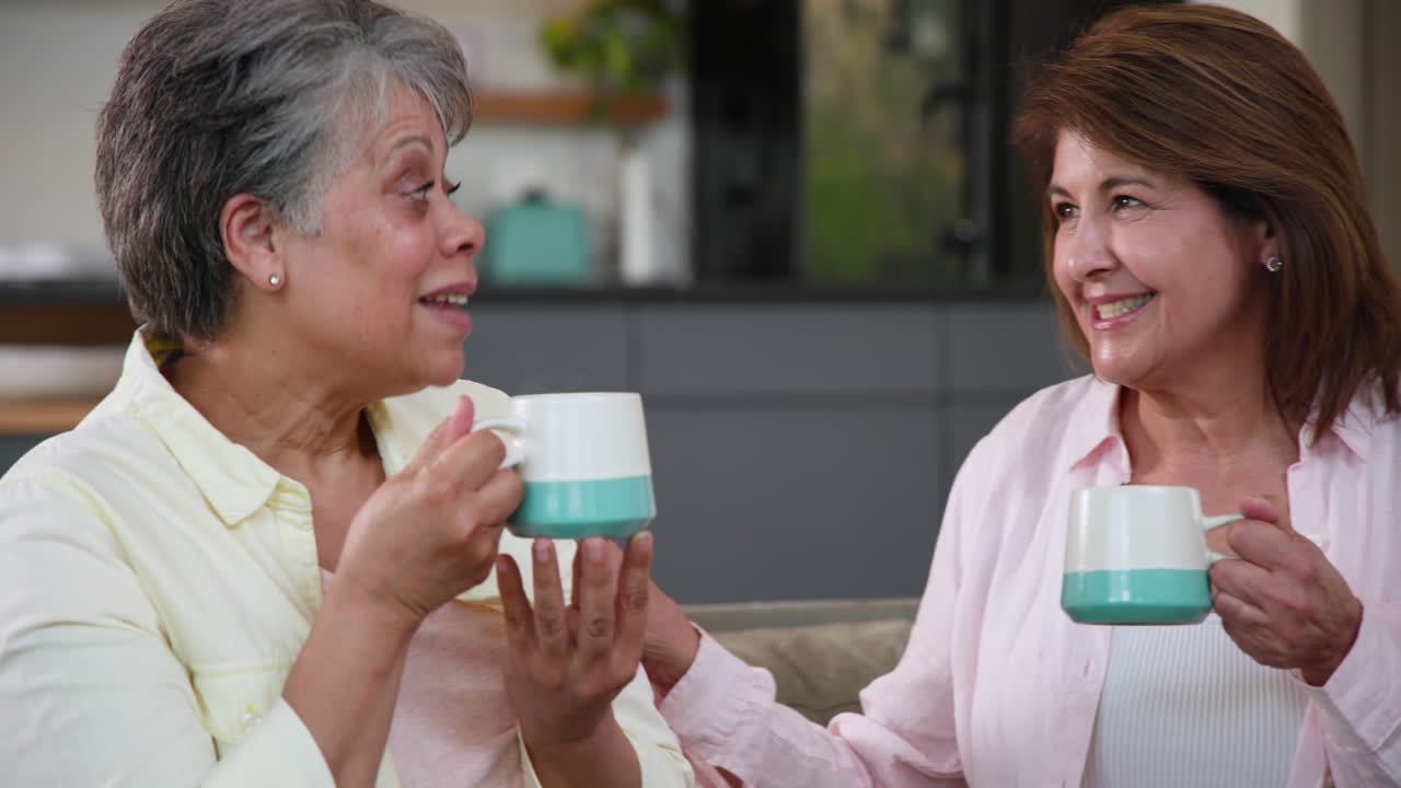 Senior women enjoying coffee together at home, sharing joyful conversation