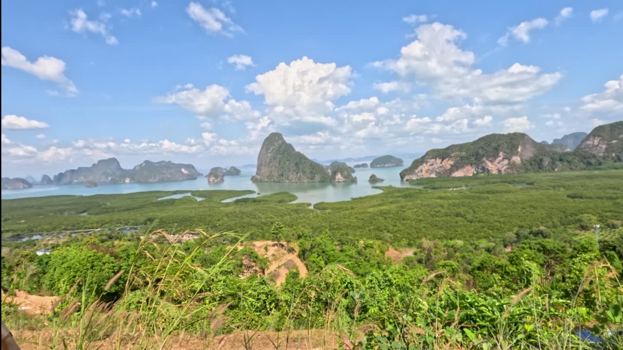 Camera moves through wicker arch revealing lush mangroves, dramatic limestone cliffs, and blue sky