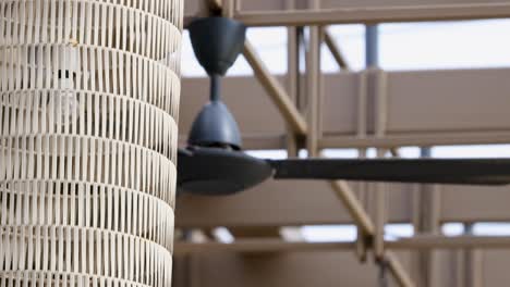 ceiling fan spins slowly in a bright, modern hotel atrium with wicker decor and natural lighting