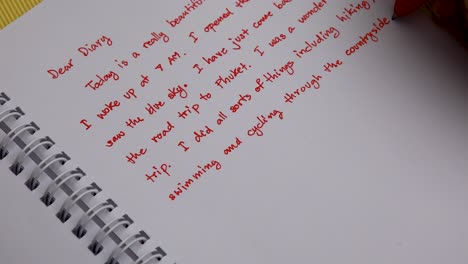 handwriting a diary with a red pen overhead shot close up of woman's hand