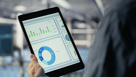 close up of data center employee checking infrastructure diagnostics on tablet