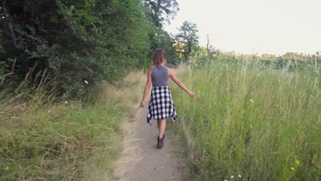 Cute-hipster-girl-walking-down-a-path,-shot-handheld