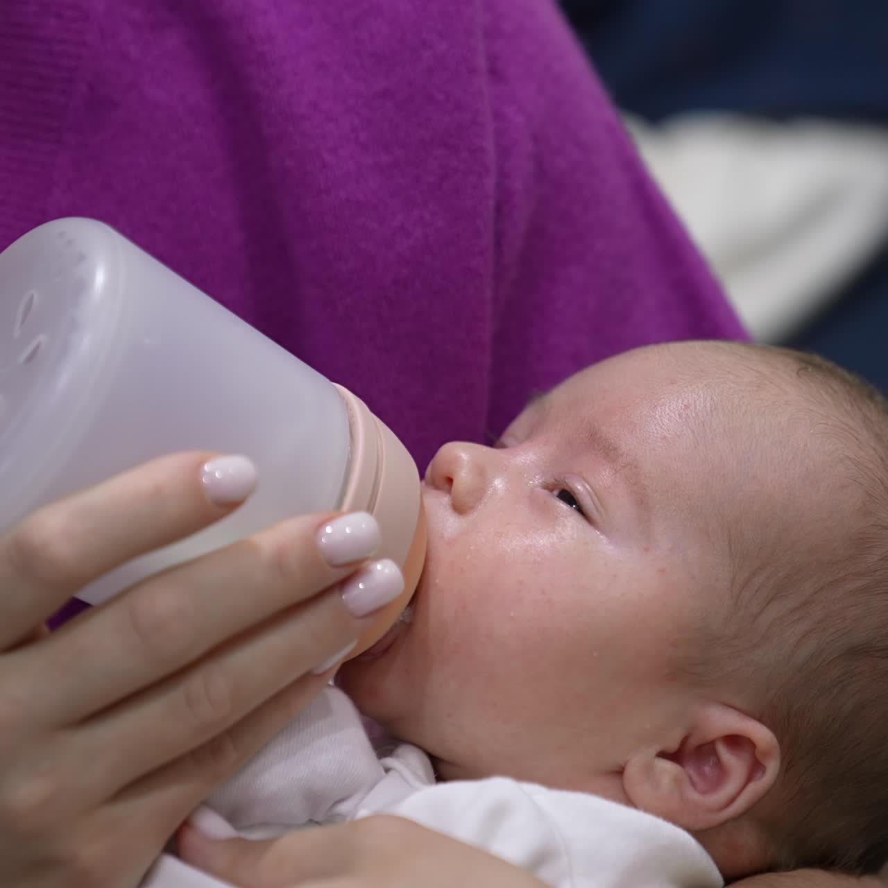 Newborn baby boy having meal and slowly falling asleep. Tiny boy in mother's hands going to sleep while feeding. Adorable kid close up