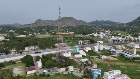 aerial view of a communication tower, highway, and town in a mountainous landscape