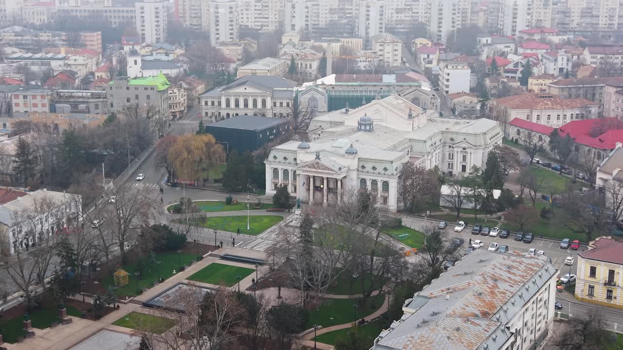 Vista de drone sobre o centro de Iasi com foco no edifício do Teatro Vasile Alecsandri, arquitetura clássica com colunas, praça verde adjacente