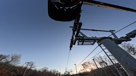 mtb rider looks and waves at camera on chairlift going up mountain sunset