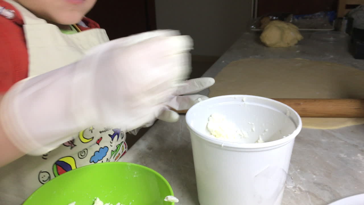 primer plano de un niño triturando queso feta en un tazón