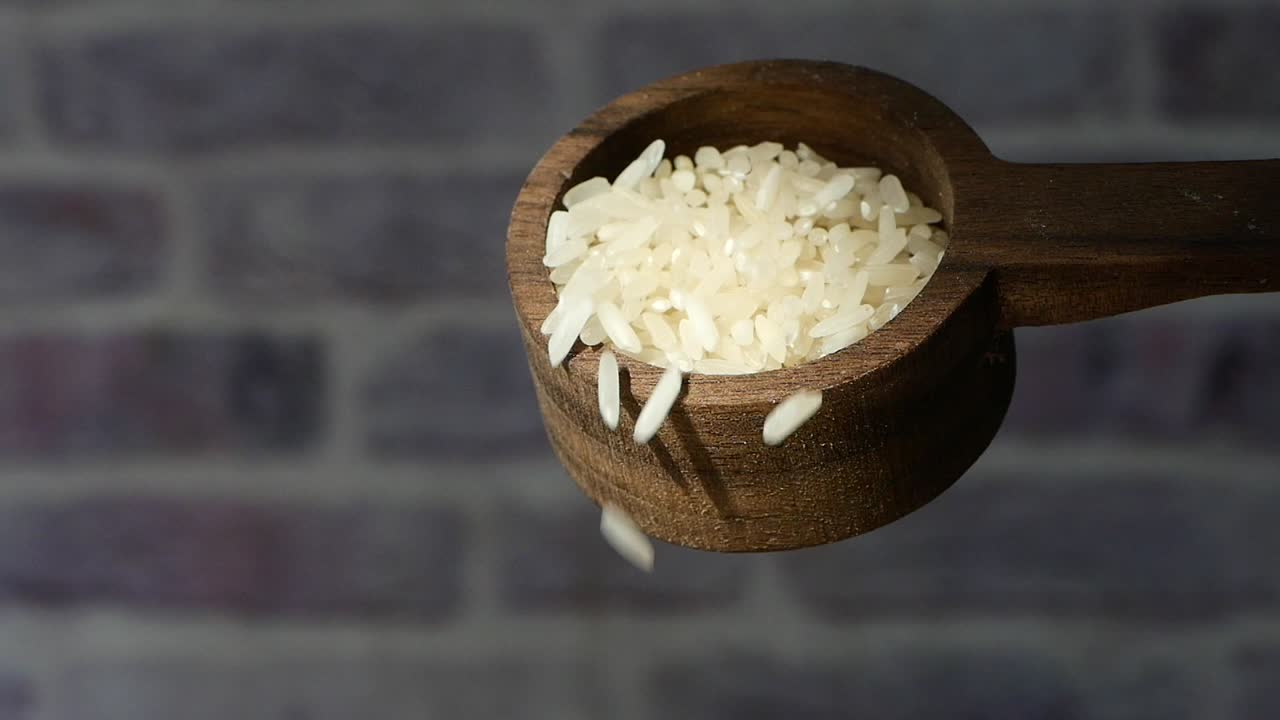 arroz blanco derramado de una cuchara de madera
