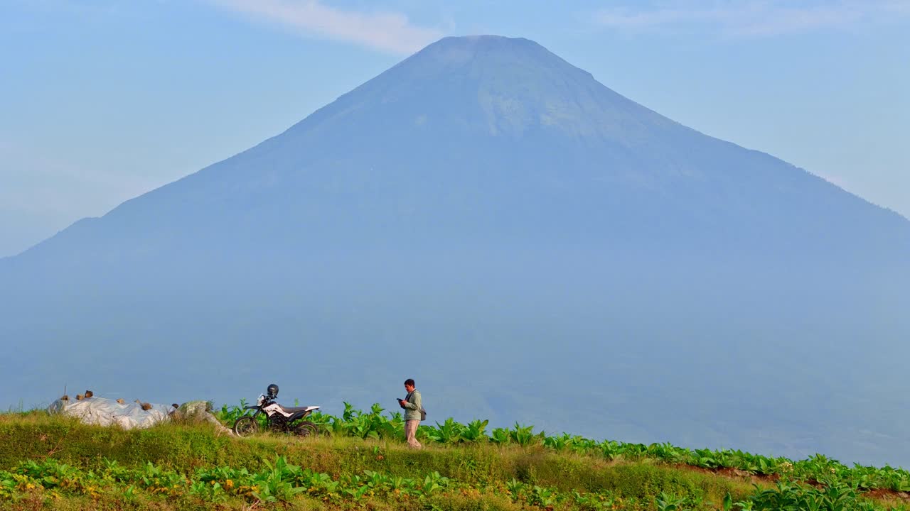 A man walking on the road with huge mountain on the background.