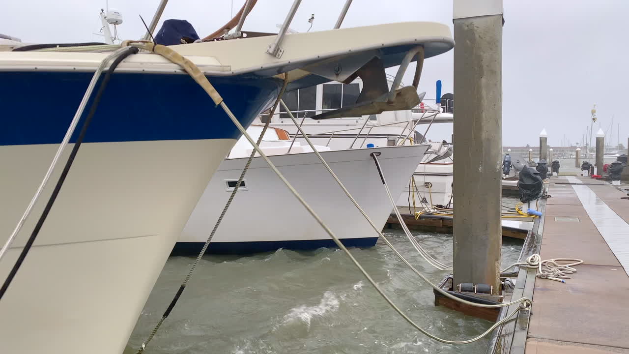 barcos amarrados en el muelle de la marina balanceándose en la marejada de la tormenta de huracán antes de tocar tierra