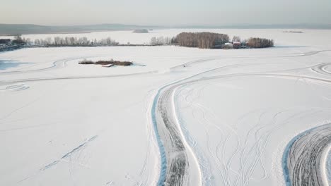 aerial view of a car driving on a frozen lake track in winter