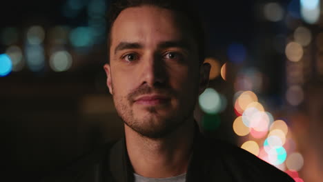 portrait attractive young caucasian man on rooftop at night smiling happy enjoying urban nightlife with bokeh city lights in background