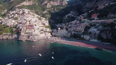aerial drone shot flying toward beach and buildings in positano, italy