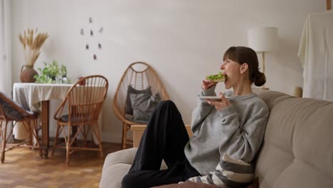 woman eating sandwich on sofa