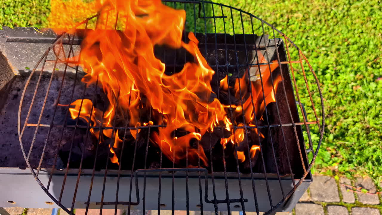 Charcoal grill with open flames and glowing coals burning hot at start of outdoor cookout