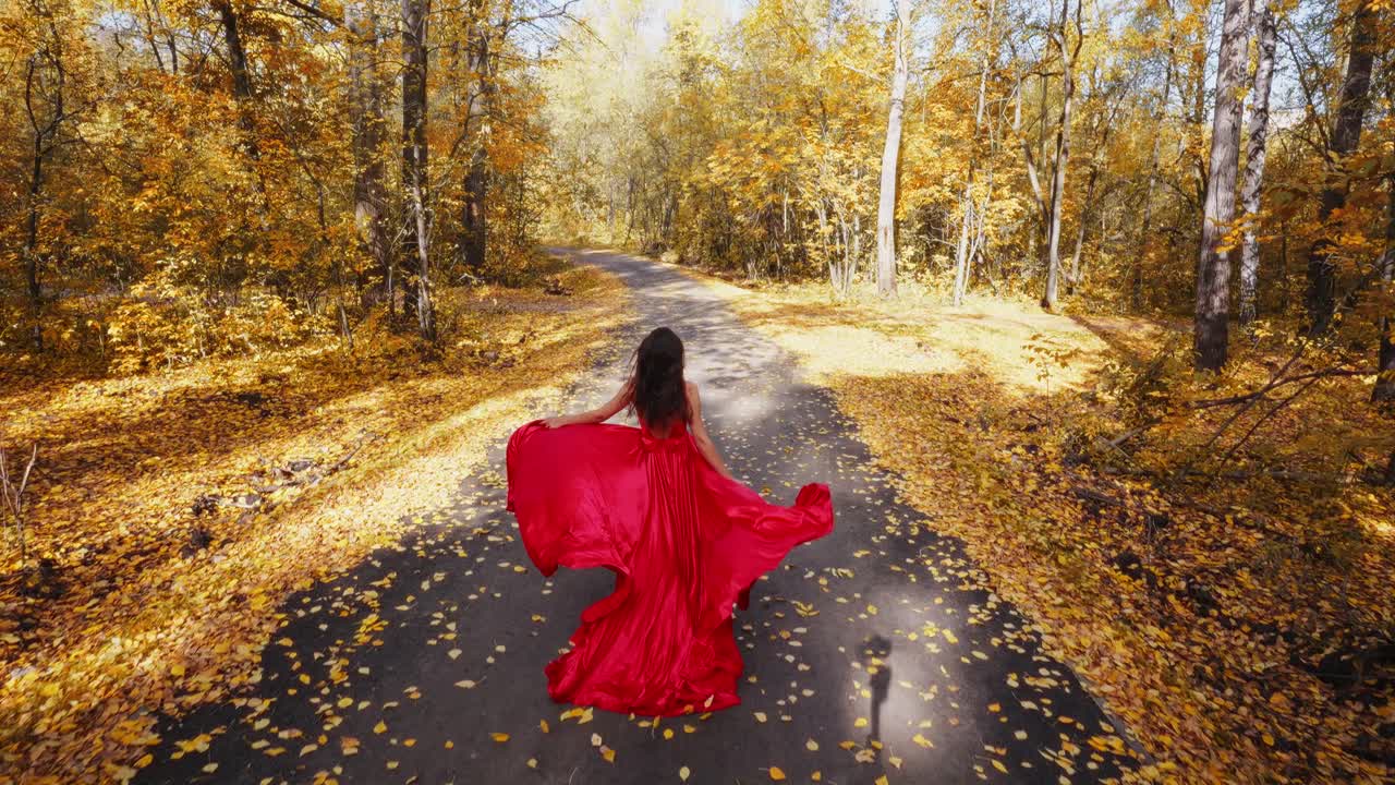 A Graceful Figure in a Flowing Red Dress Dances Through an Autumn Forest Path, Surrounded by Vibrant Fall Foliage and Sunlight Filtering Through the Trees