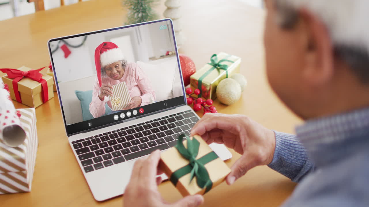 산타 모자를 입은 남성이 아프리카계 미국인 여성과 노트북으로 비디오 통화를 하고 있습니다.